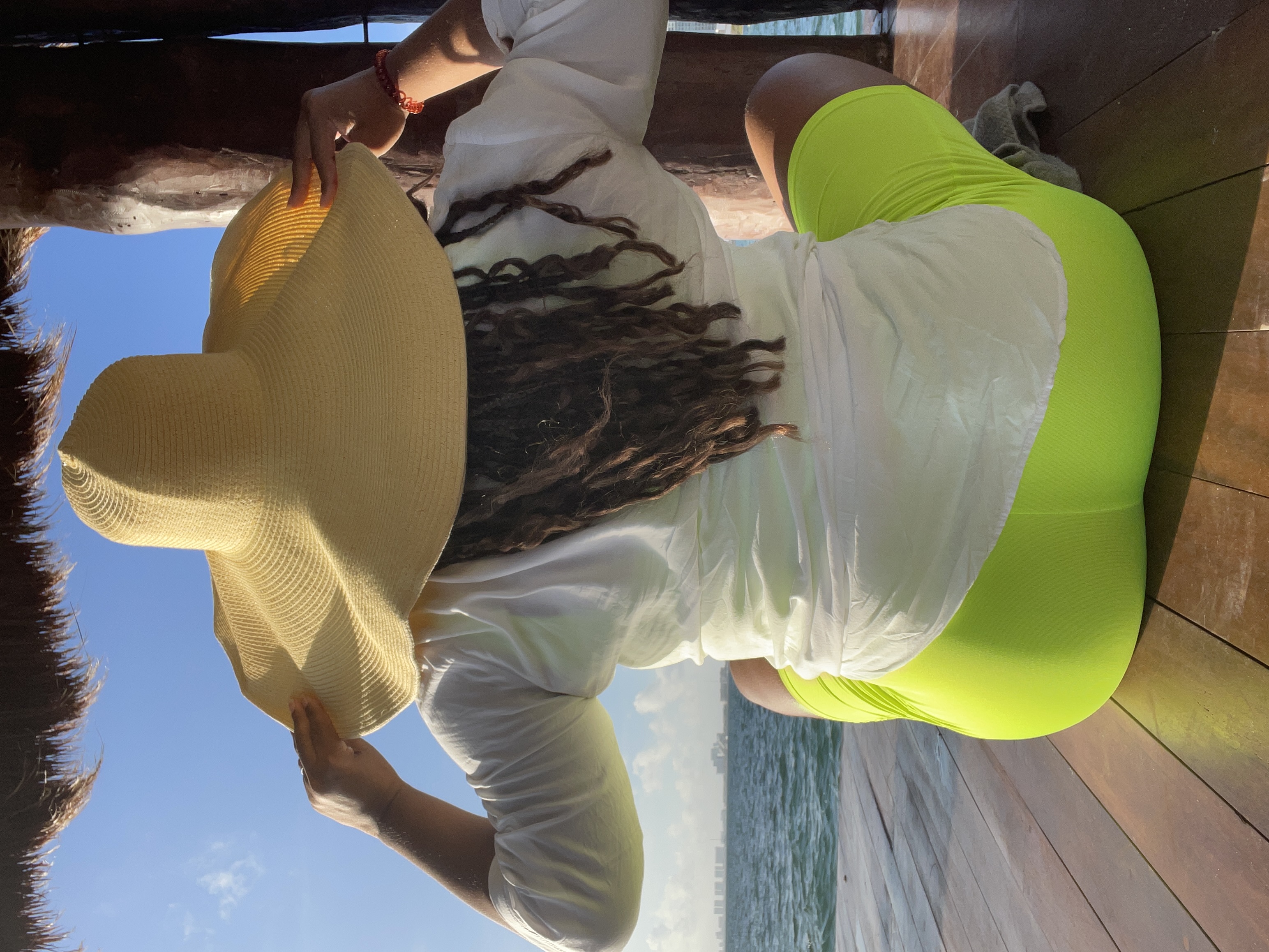 woman sitting holding hat down looking at ocean