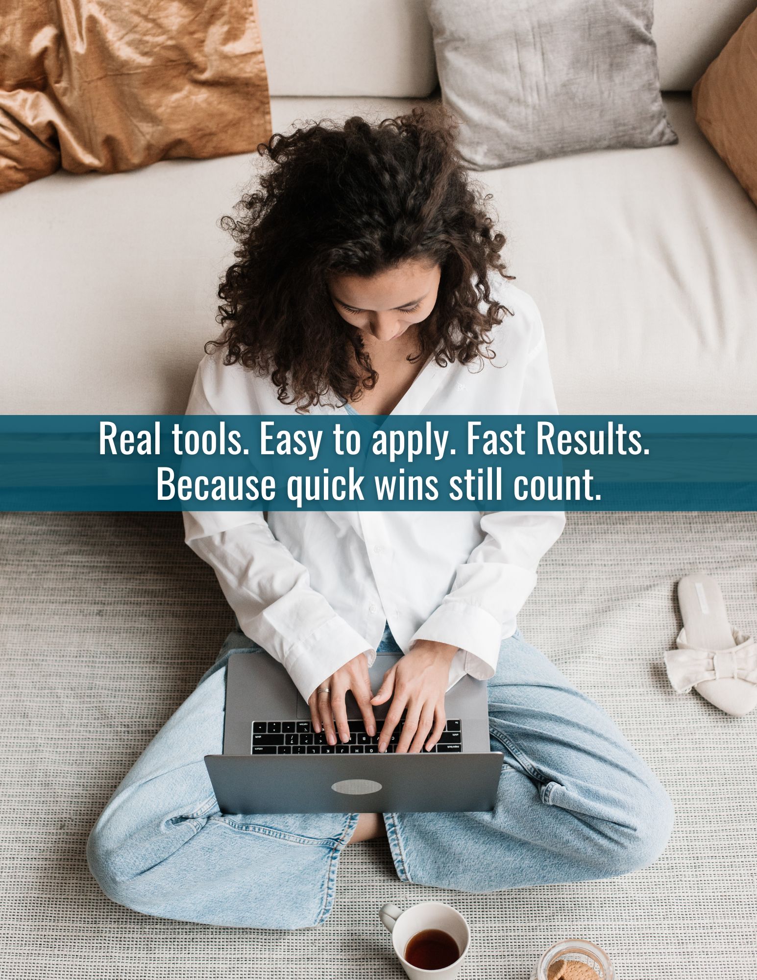 Woman sitting on floor working on computer with cup of coffee