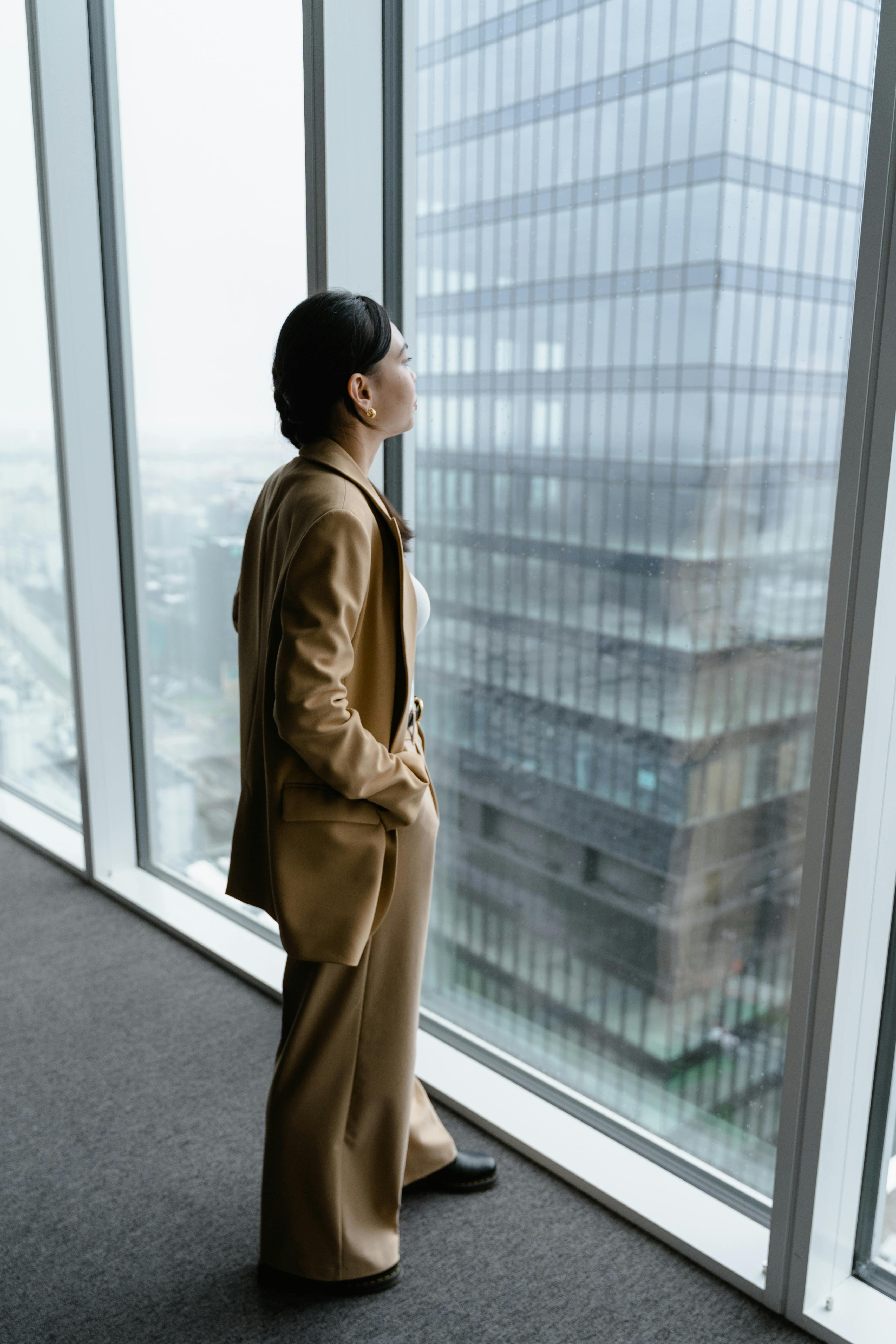 Business woman looking out of ceiling to floor office window